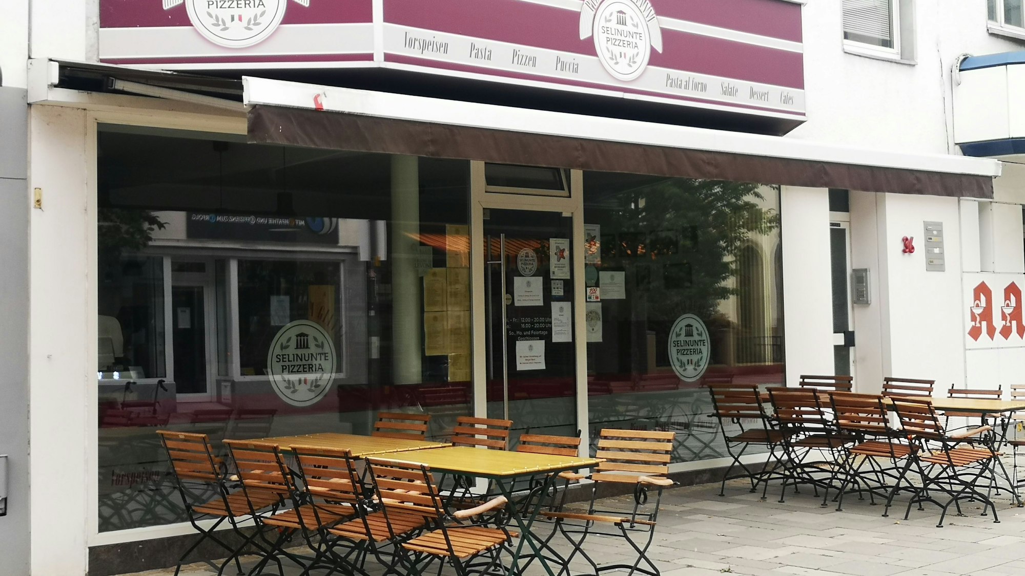 Die Pizzeria Selinunte Da Gianni in der Wesselinger Bahnhofstraße gehört zu den beliebtesten im Rhein-Erft-Kreis. Hier ist sie von außen zu sehen. Eine Jalousie ist eingefahren, draußen stehen Stühle und Tische.