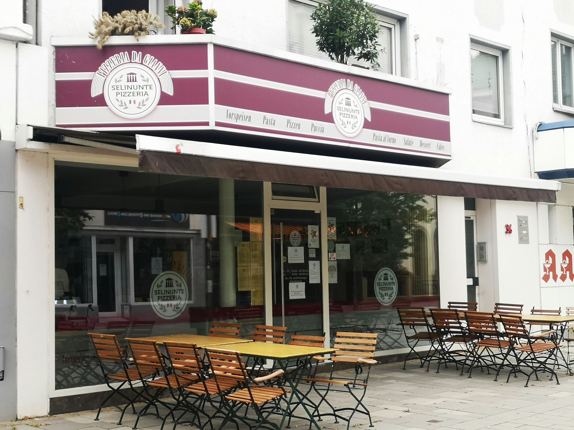 Die Pizzeria Selinunte Da Gianni in der Wesselinger Bahnhofstraße gehört zu den beliebtesten im Rhein-Erft-Kreis. Hier ist sie von außen zu sehen. Eine Jalousie ist eingefahren, draußen stehen Stühle und Tische.
