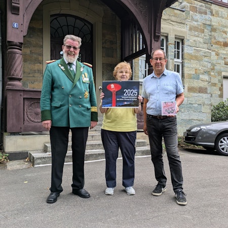 Eine Frau und zwei Männer stehen vor einem historischen Gebäude.