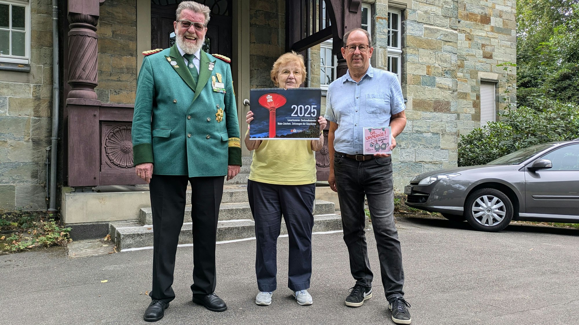Eine Frau und zwei Männer stehen vor einem historischen Gebäude.