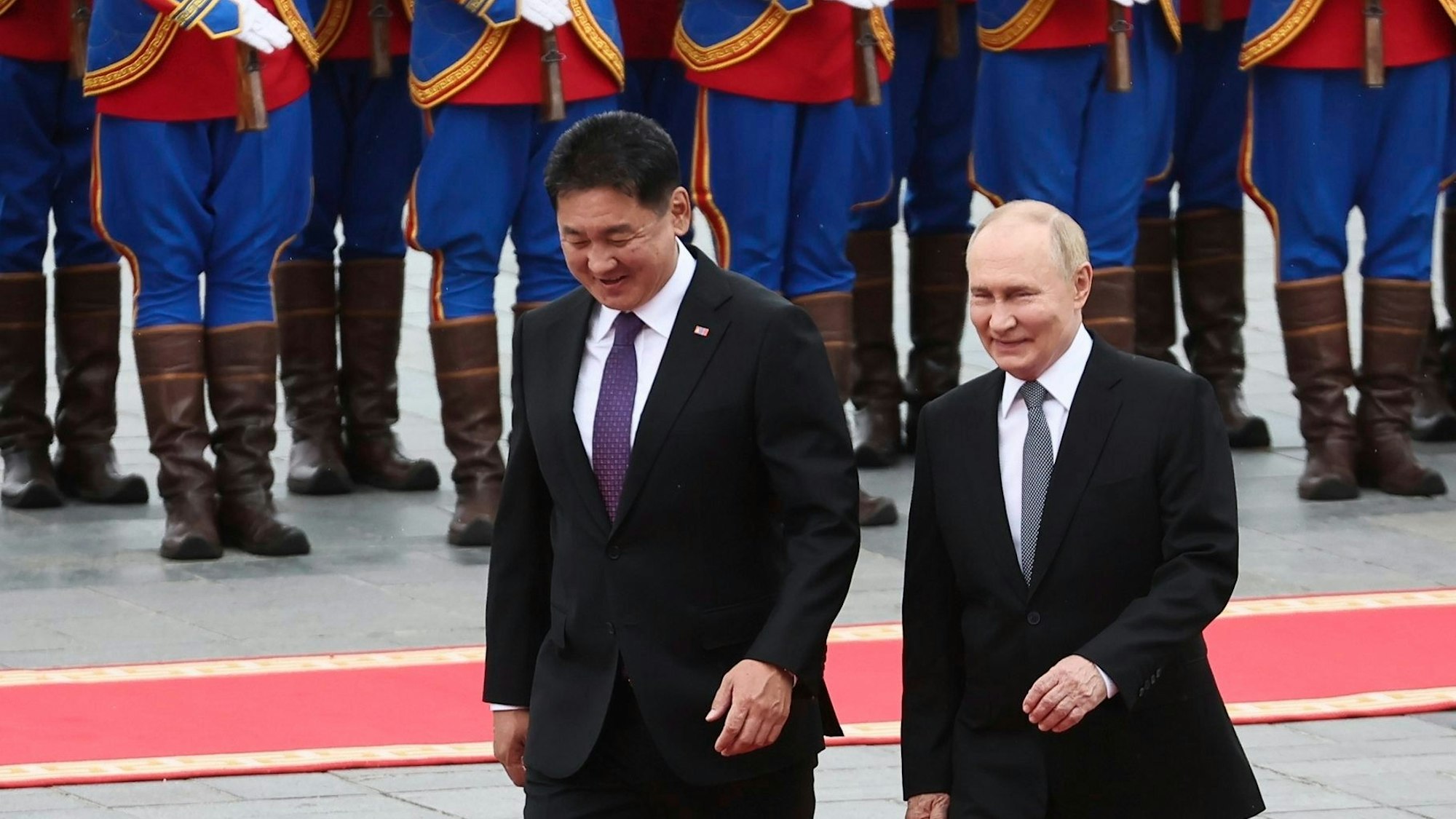 Der russische Präsident Wladimir Putin (r.) geht mit dem mongolischen Präsidenten Ukhnaagiin Khurelsukh während der Begrüßungszeremonie über den Sukhbaatar-Platz in Ulan Bator.