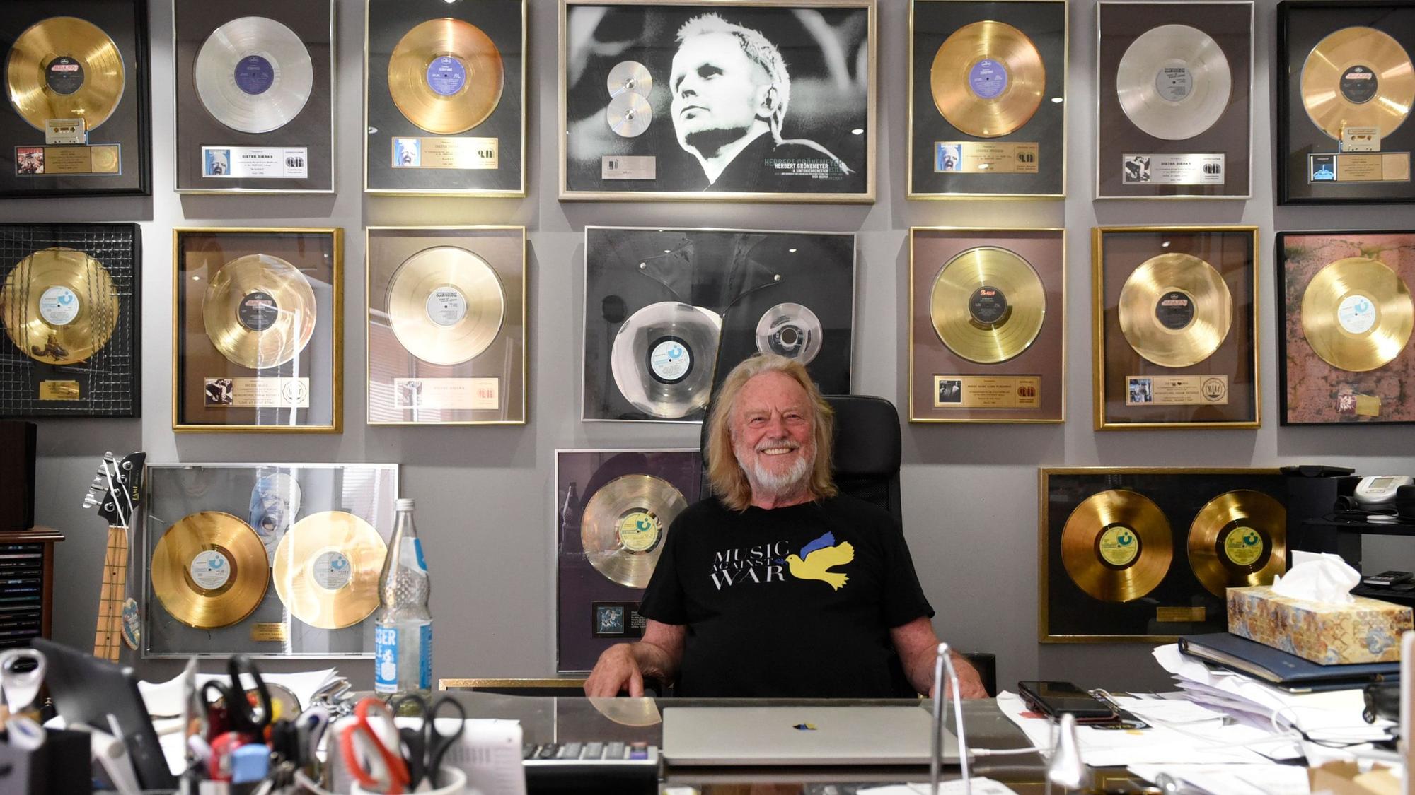 Zu sehen ist Dieter Dierks vor vielen goldenen Schallplatten.