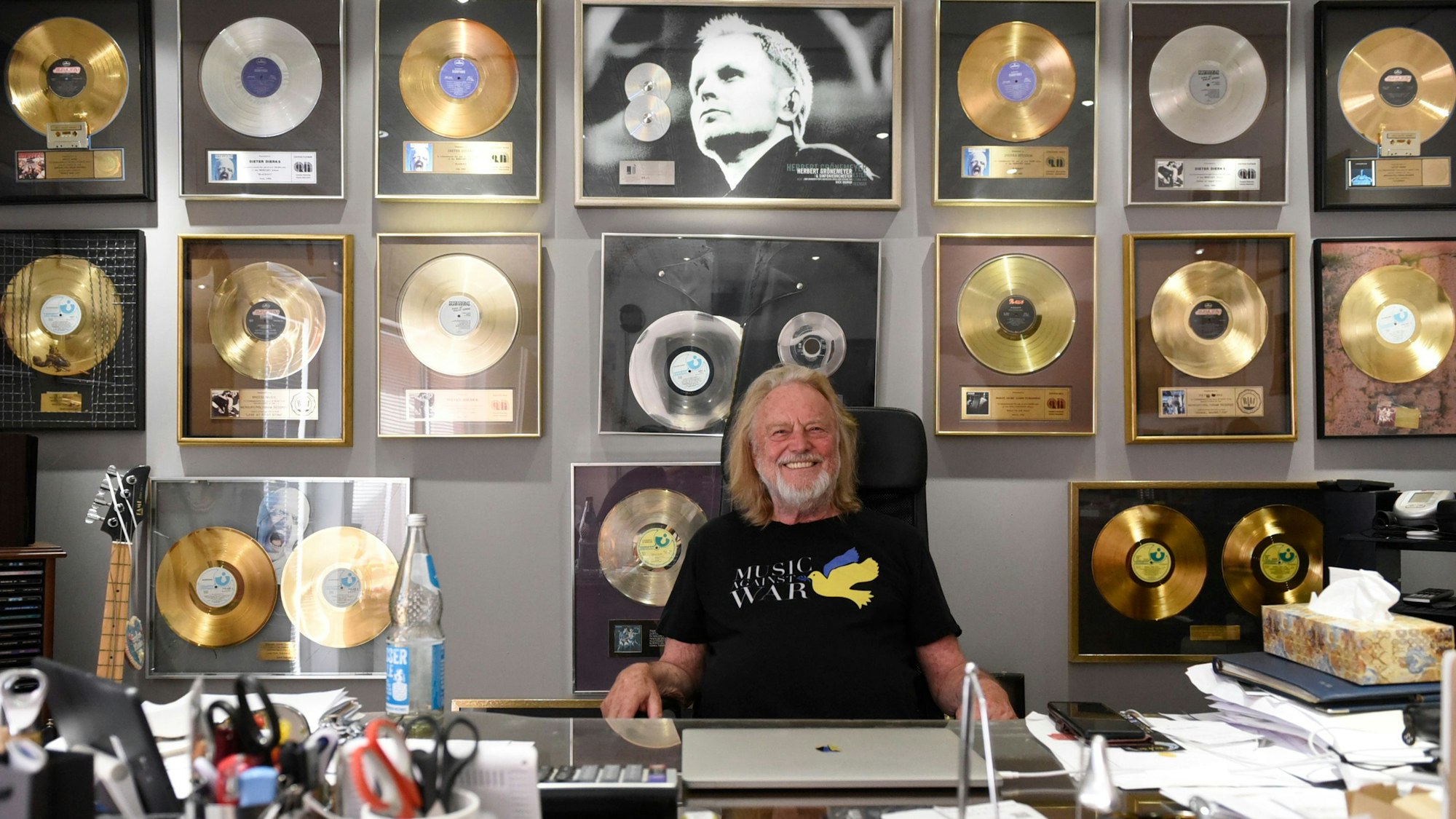 Zu sehen ist Dieter Dierks vor vielen goldenen Schallplatten.