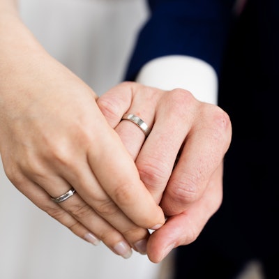 Ein frisch vermähltes Brautpaar zeigt nach der Eheschließung im Rathaus die Eheringe.