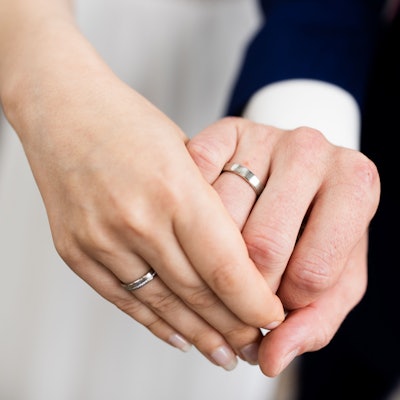 Ein frisch vermähltes Brautpaar zeigt nach der Eheschließung im Rathaus die Eheringe.