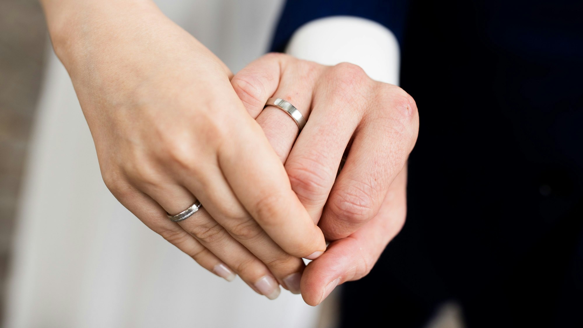 Ein frisch vermähltes Brautpaar zeigt nach der Eheschließung im Rathaus die Eheringe.