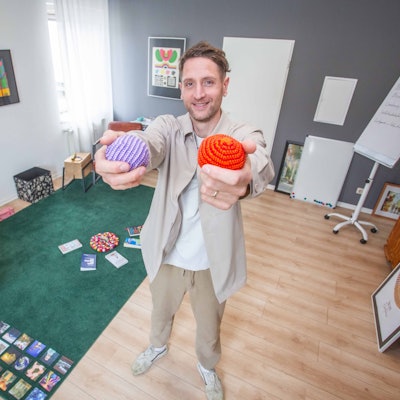 Ein Mann hält zwei Bälle in die Kamera.