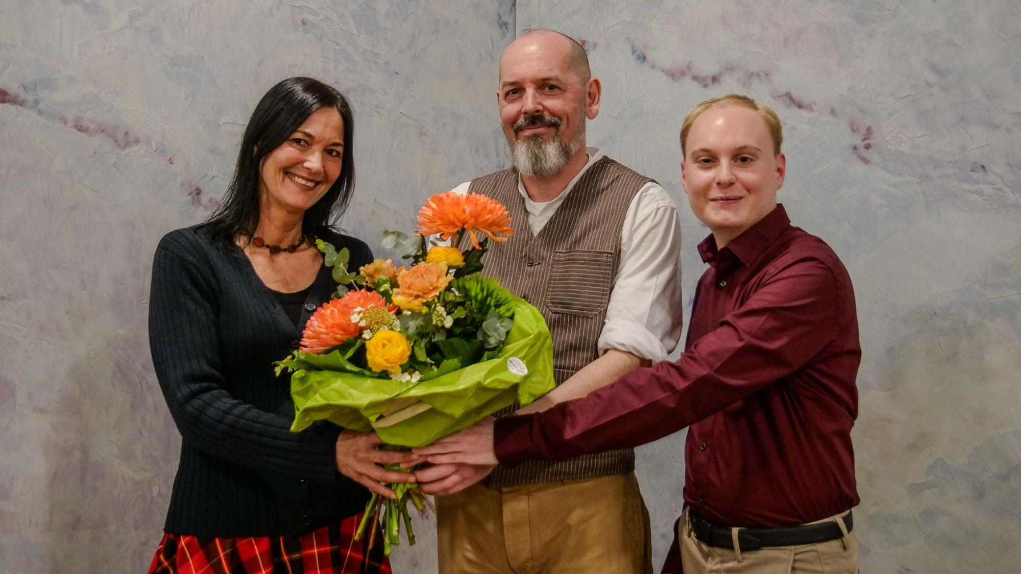 Links und rechts von Thommy Mewes übergeben Tina Conrady und Christian Schubert ihrem Kandidaten einen Strauß Blumen.