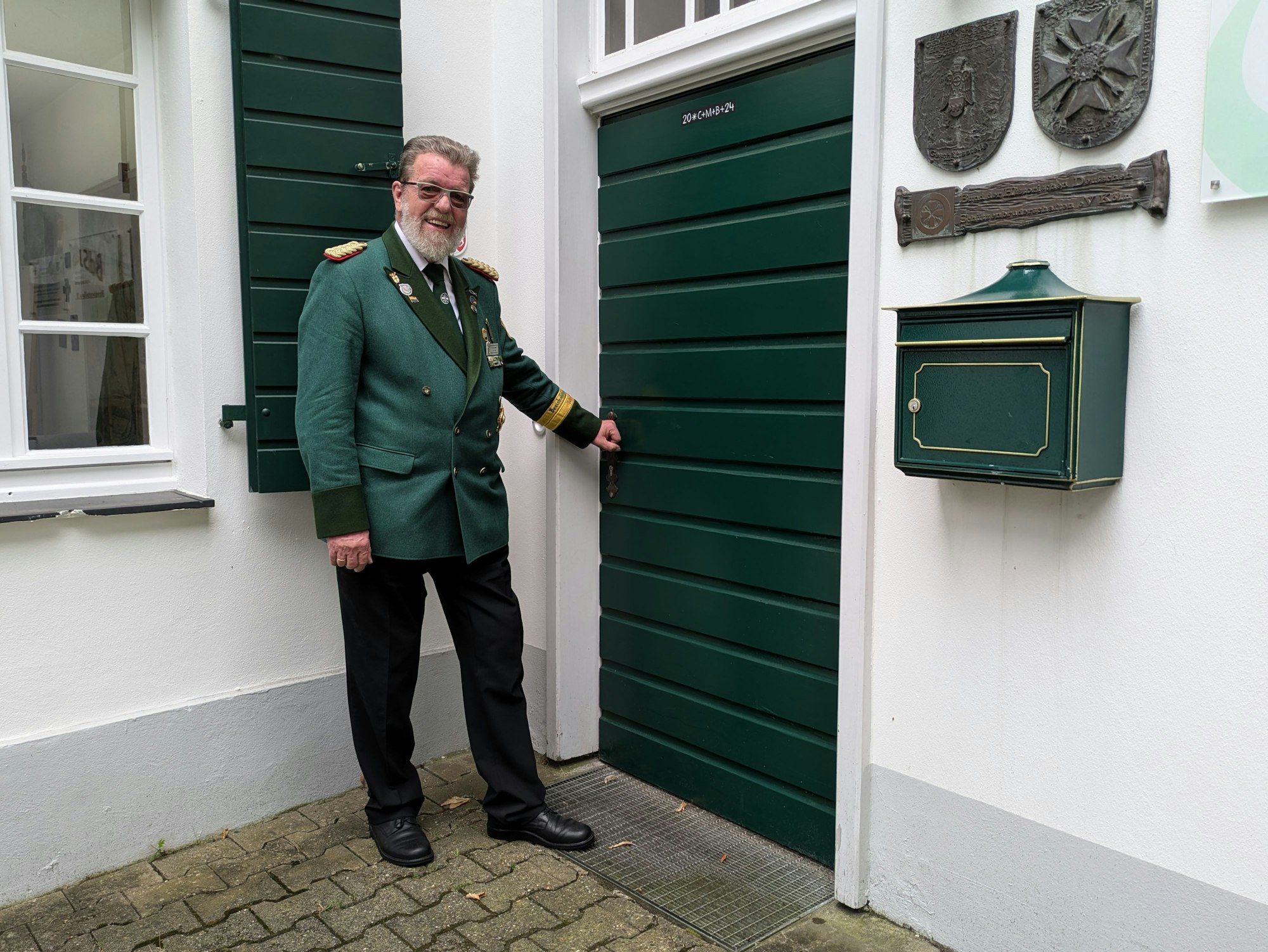 Ein Mann in Uniform steht an einer grünen Holztür.