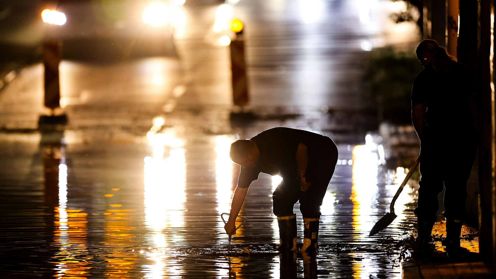 dpatopbilder - 02.09.2024, Nordrhein-Westfalen, Duisburg: Feuerwehrleute öffnen einen Gullydeckel in einer Unterführung im Stadtteil Buchholz, damit das Wasser nach einem Unwetter ablaufen kann. Foto: Christoph Reichwein/dpa +++ dpa-Bildfunk +++