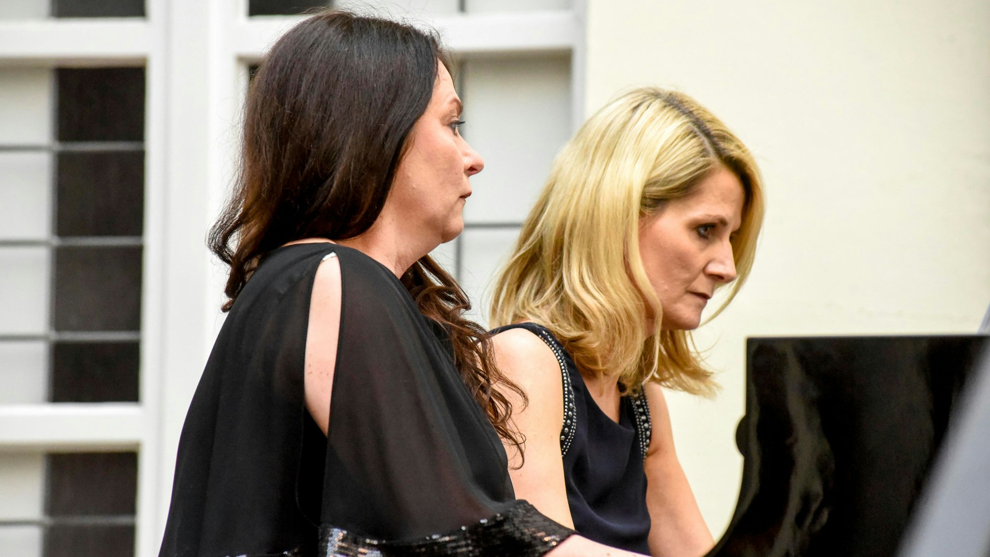 Zwei Frauen spielen gemeinsam auf einem Flügel. Sie sind in Schwarz gekleidet.