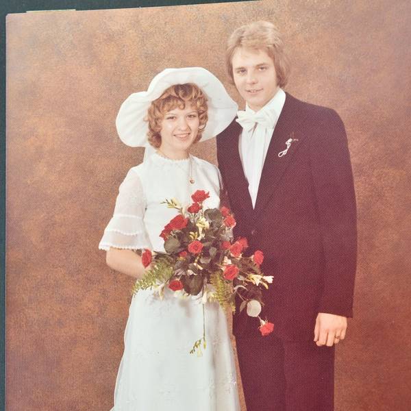 Eine junge Frau und ein junger Mann tragen auf einem Foto aus den 1970er Jahren Kleid und Anzug.