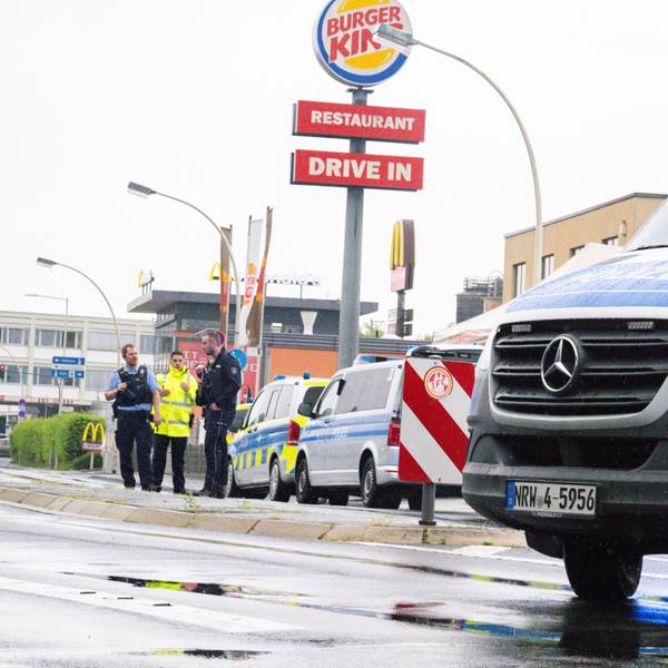 Einsatzkräfte der Polizei stehen mit Einsatzwagen auf einer Straße.