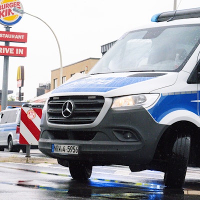 Einsatzkräfte der Polizei stehen mit Einsatzwagen auf einer Straße.