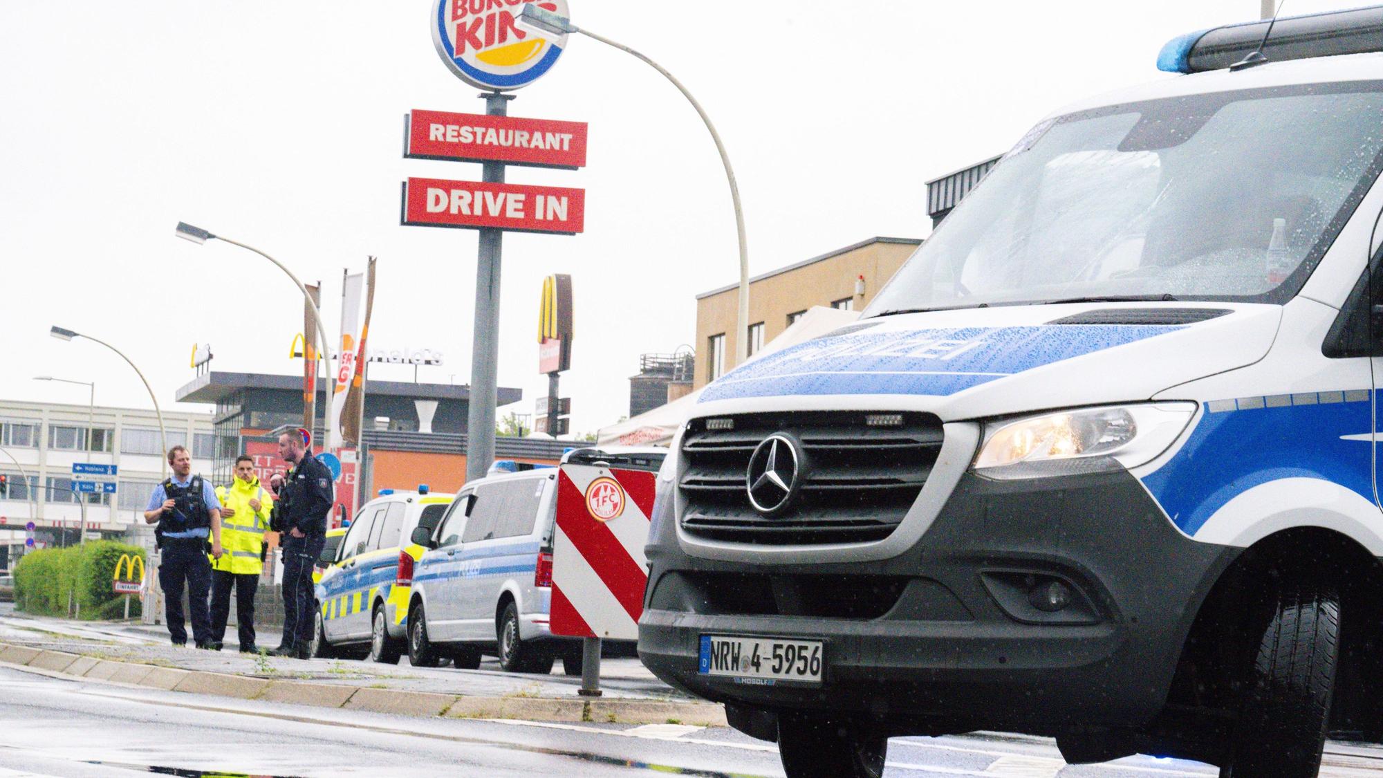 Einsatzkräfte der Polizei stehen mit Einsatzwagen auf einer Straße.