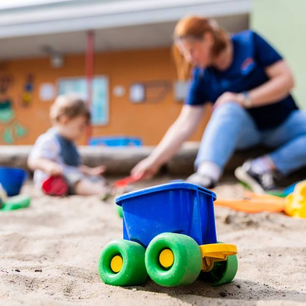 Ein Kind spielt mit einer Erzieherin im Sandkasten einer Kita.