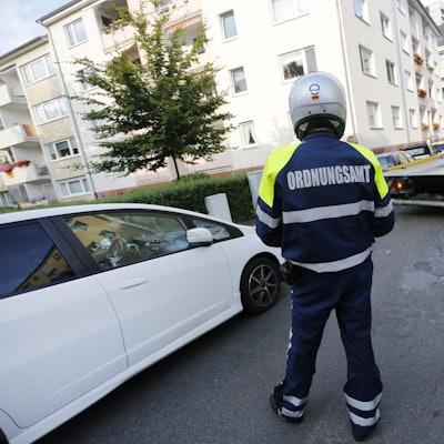 Das Foto zeigt eine Person mit dem Schriftzug Ordnungsamt hinten auf der Jacke vor einem Pkw und einem Abschleppwagen.