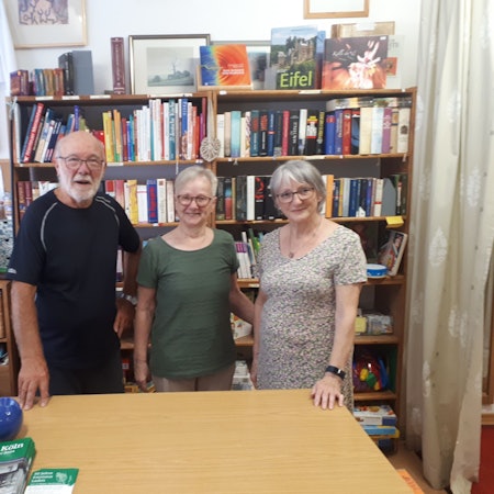 Zu sehen sind Rolf Eischeid (l.) hinter der Theke mit zwei weiteren Ehrenamtlerinnen.