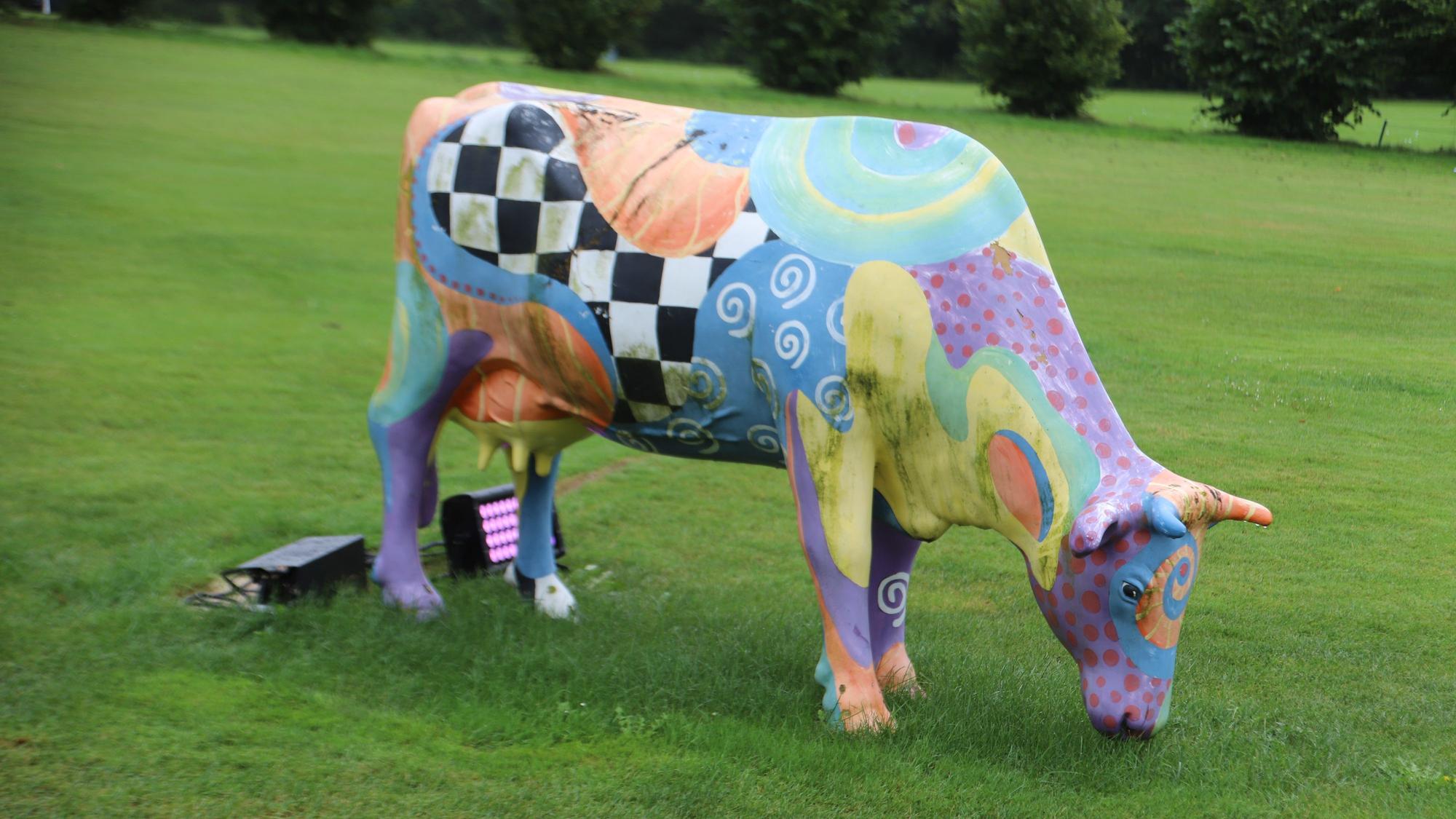 Eine bunt bemalte Kuh steht auf einer Wiese.