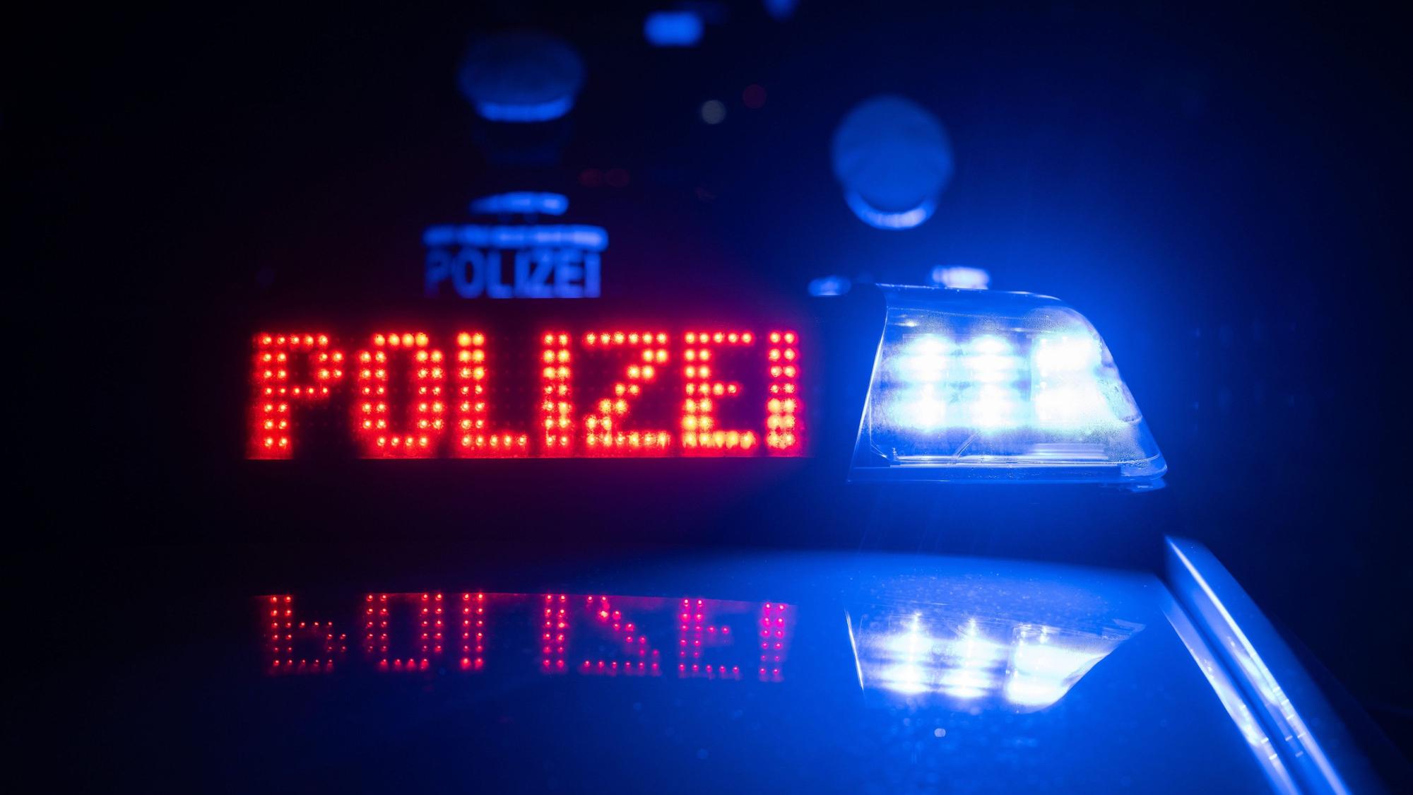 Zwei Polizisten stehen vor einem Polizeifahrzeug.