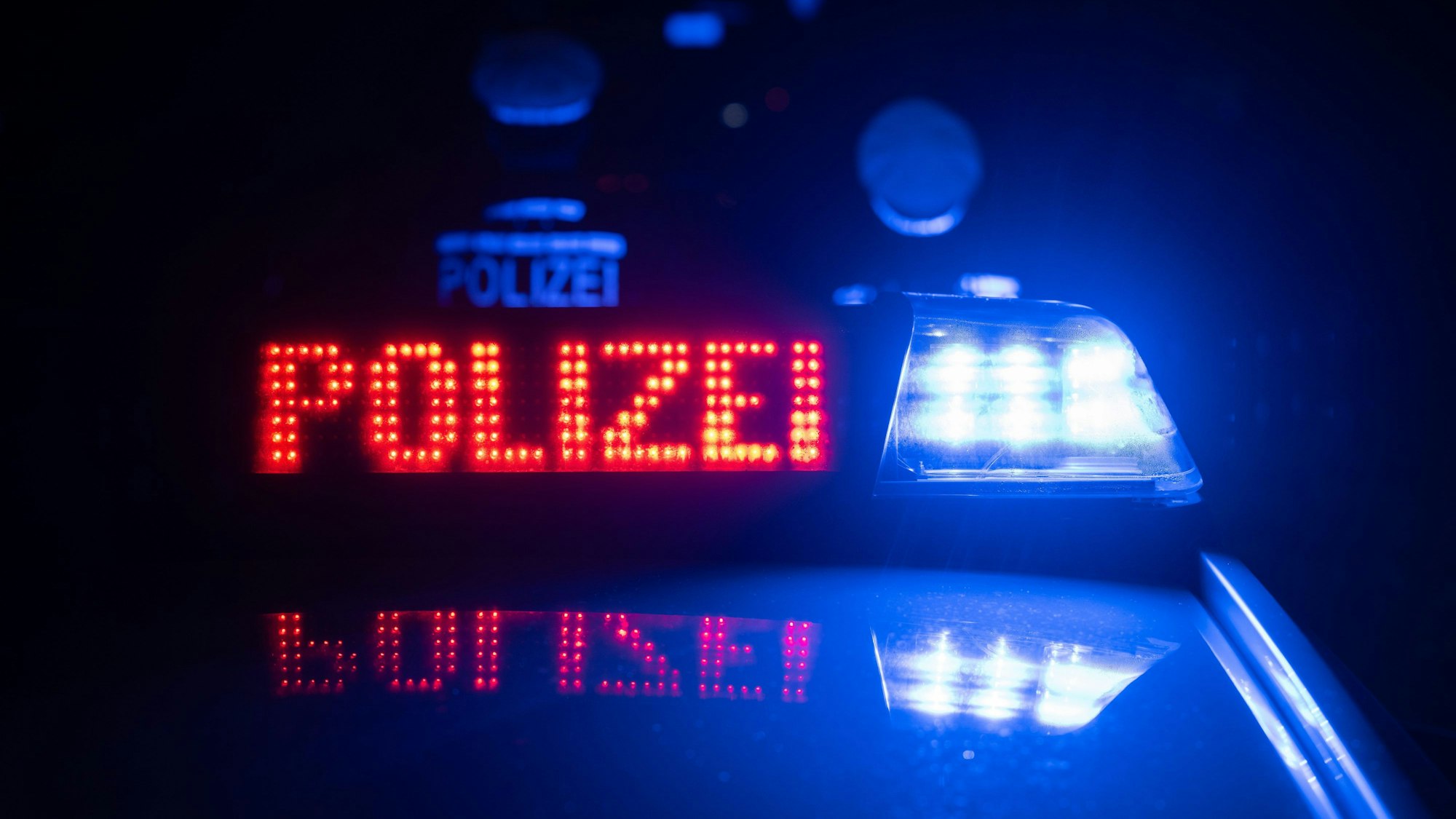 Zwei Polizisten stehen vor einem Polizeifahrzeug.