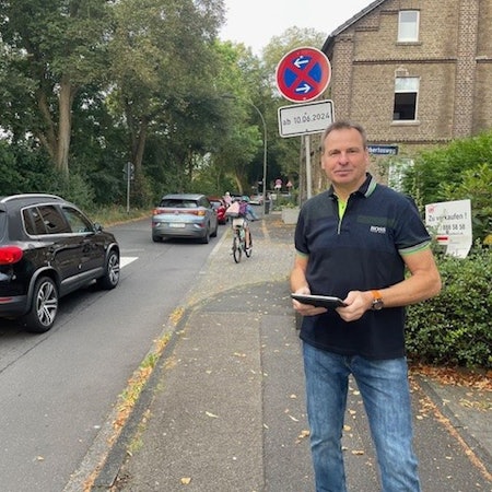 Ein Mann mit einem Tablet steht an einer Straße