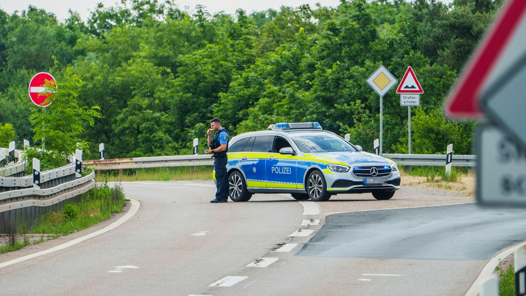 Ein Polizeiwagen sperrt den Verkehr (Symbolfoto). Der 20-Jährige wurde auf einer Bundesstraße durch Messerstiche getötet.