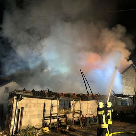 Feuerwehrleute löschen ein Wirtschaftsgebäude eines Bauernhofs bei Kürten-Dürscheid.