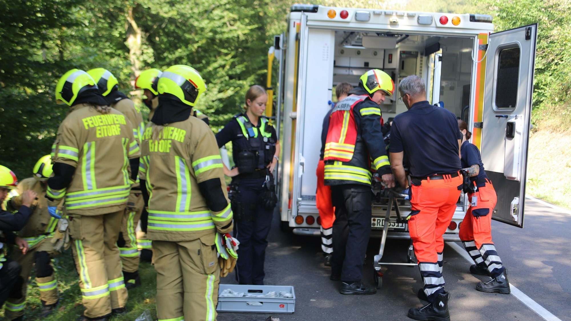 Rettungskräfte und ein Feuerwehrmann schieben den Verletzten in einen Rettungswagen.
