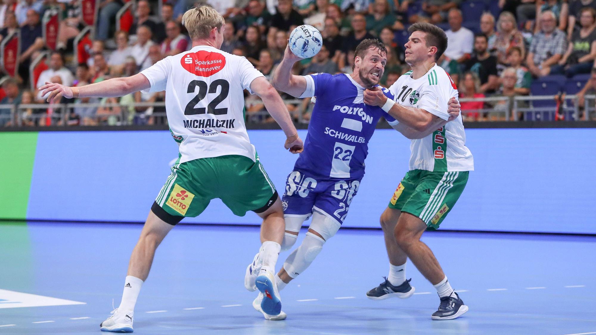 Handballer Kentin Mahé setzt sich im Angriffsspiel zwischen zwei gegnerische Spieler aus Hannover durch.