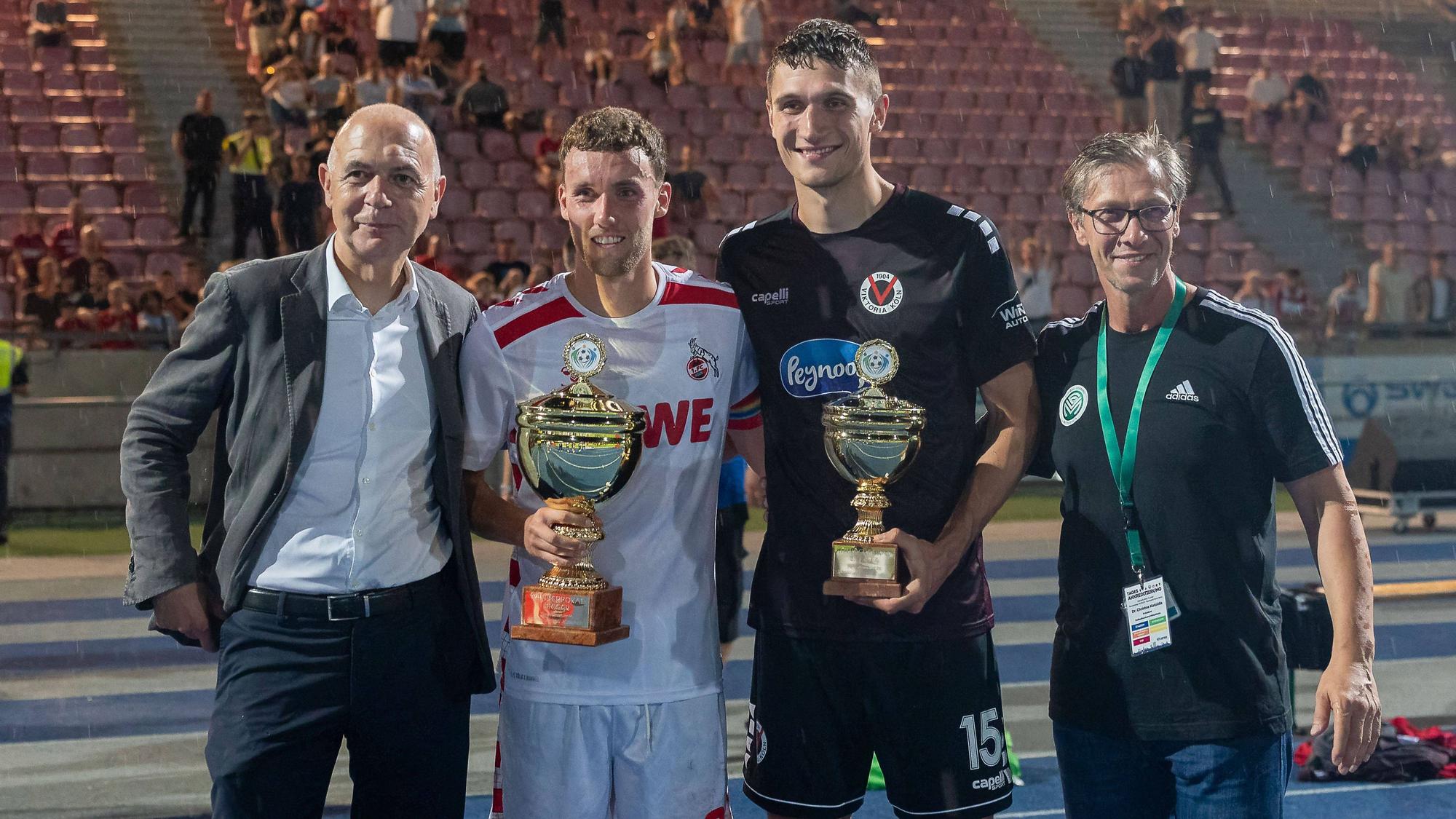 DFB-Präsident Bernd Neuendorf mit FC-Kapitän Luca Waldschmidt, Viktorias Spielführer Christoph Greger und FVM-Chef Christos Katzidis bei der Siegerehrung (v.l.)