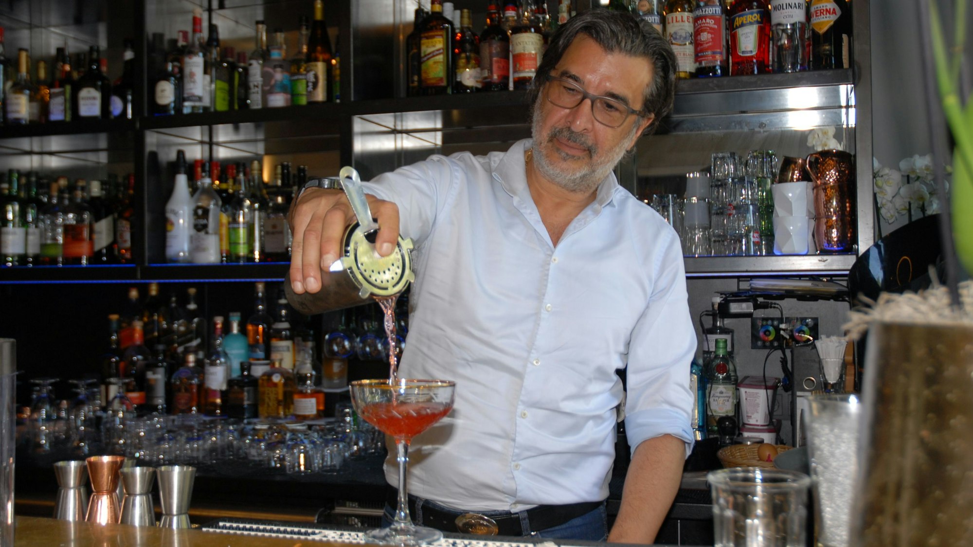 Ein Mann füllt ein rotes Getränk in ein Glas.