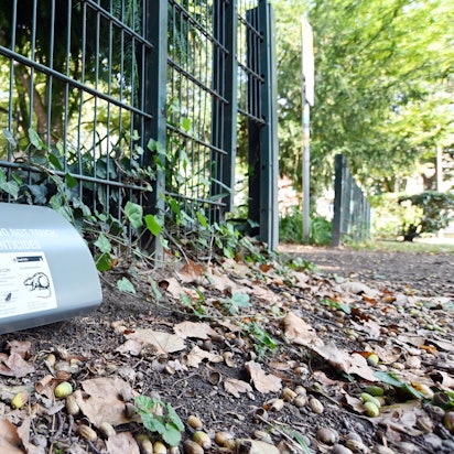 Eine graue Box liegt auf dem Parkboden, darauf sind Warnschriften