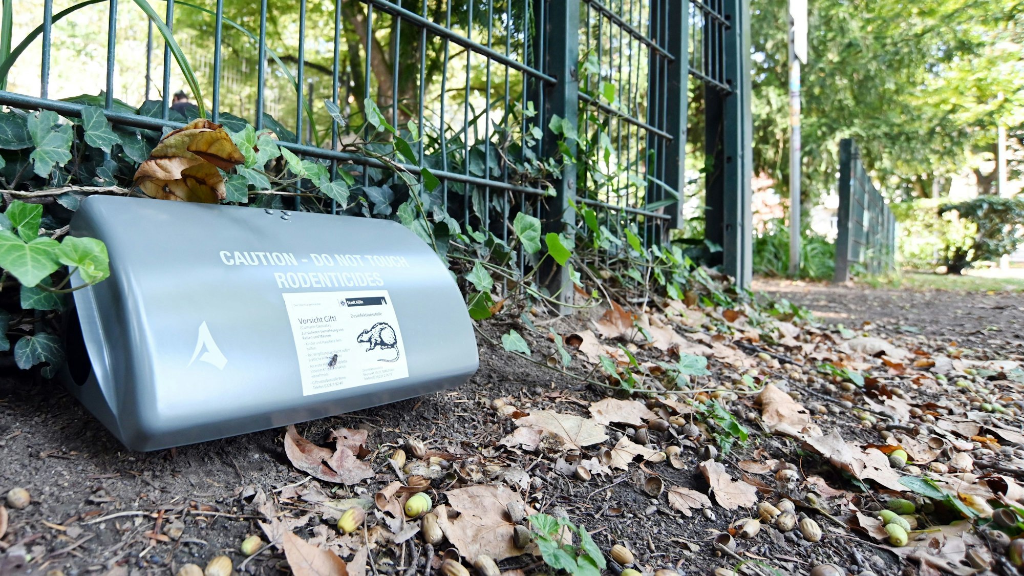 Eine graue Box liegt auf dem Parkboden, darauf sind Warnschriften