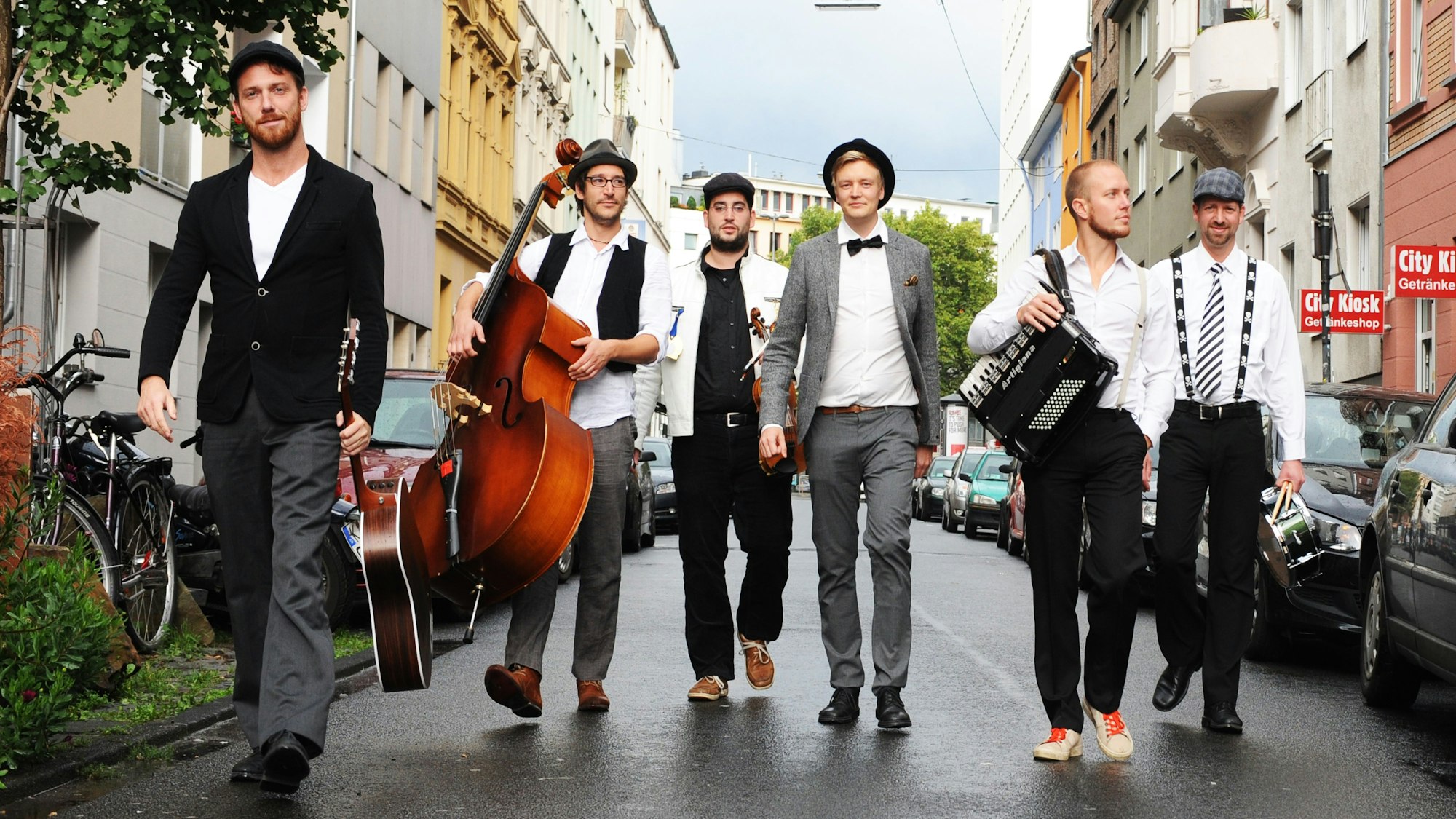 sechs Musiker der Band „Kommando MundArt“ laufen durch eine Straße in Köln