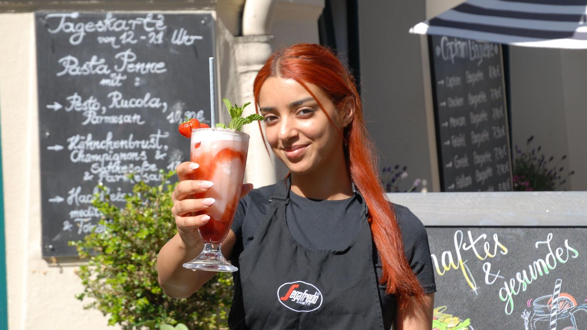 Eine Frau hält einen rosaroten Milchshake in der Hand.
