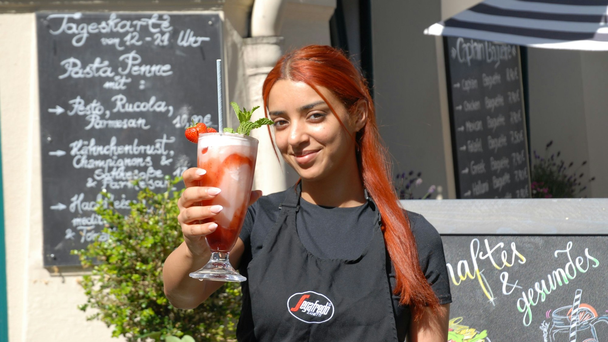 Eine Frau hält einen rosaroten Milchshake in der Hand.
