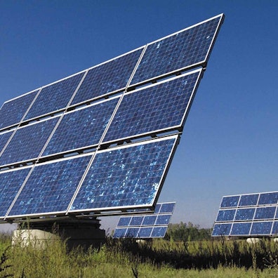 Elemente einer Photovoltaik-Anlage stehen auf einer Wiese.