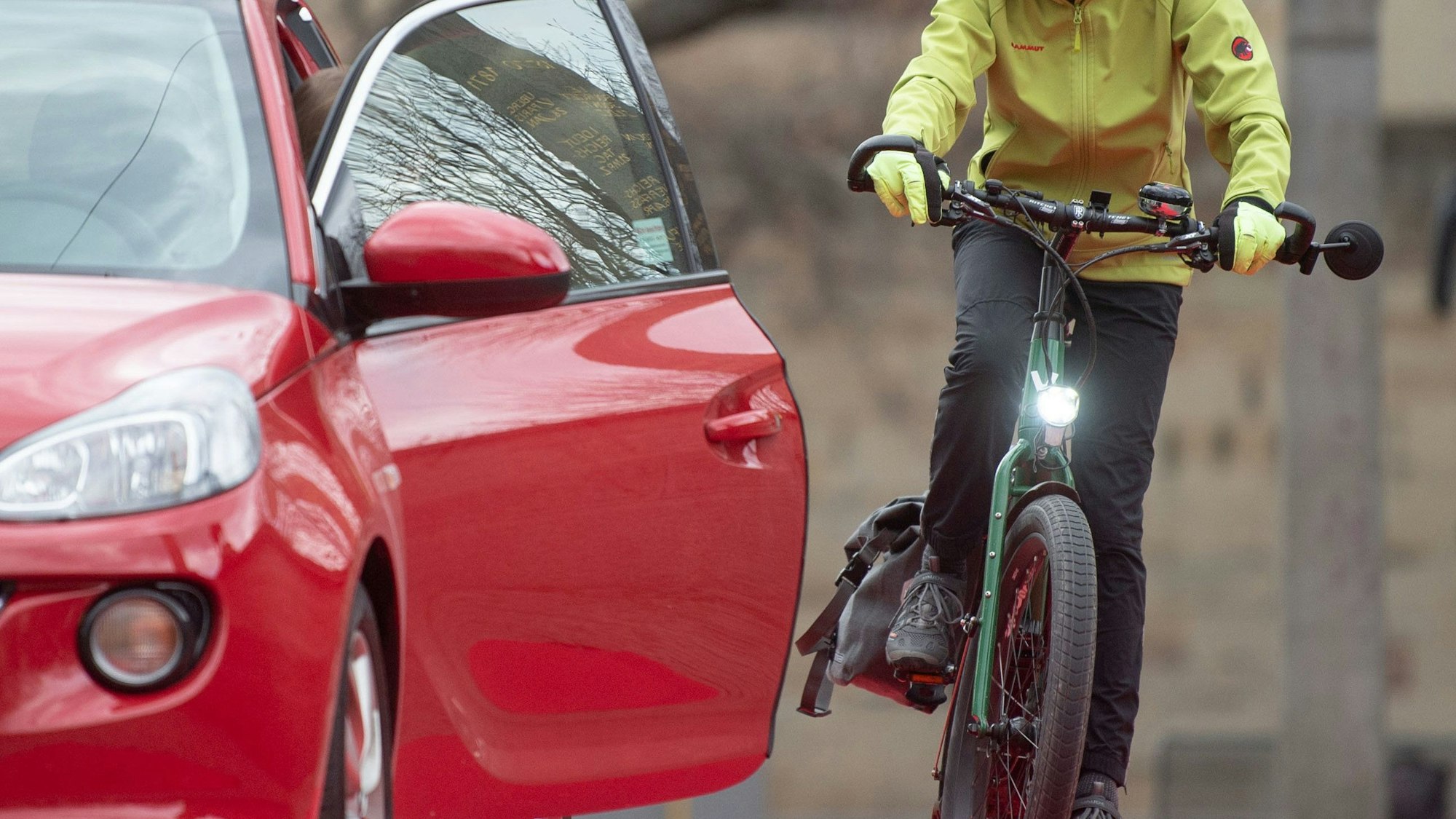 Ein Symbolbild stellt einen Dooring-Unfall dar, bei dem eine radfahrende Person von einer geöffneten Tür eines Kraftfahrzeugs erfasst wird. Das Fahrrad ist grün, das Auto rot, die Jacke der radfahrenden Person gelb.