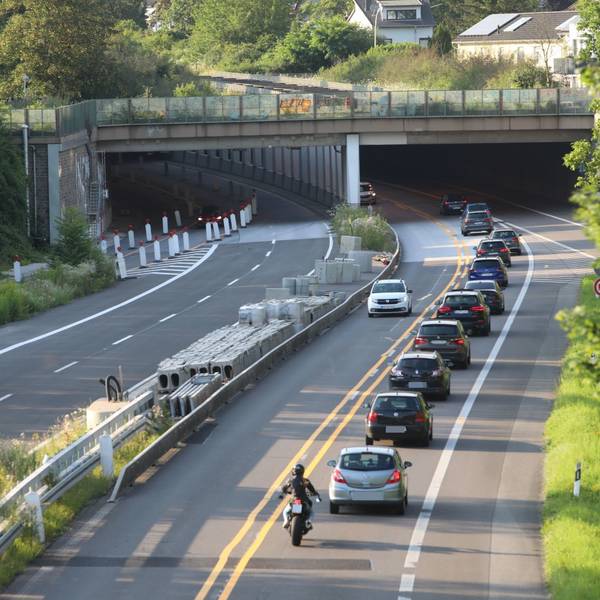 Eine vierspurige Straße, auf der die linke Hälfte für den Verkehr gesperrt ist. Im Hintergrund fahren Autos in den Tunnel Oberkassel