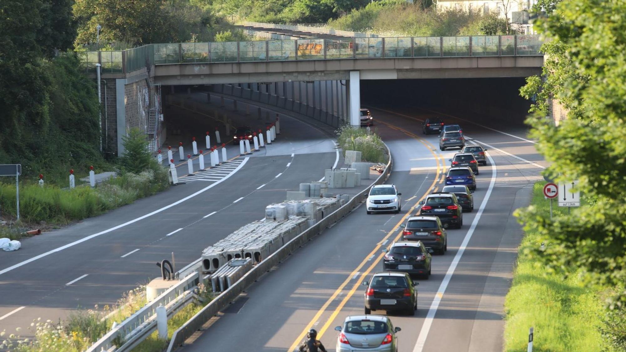 Eine vierspurige Straße, auf der die linke Hälfte für den Verkehr gesperrt ist. Im Hintergrund fahren Autos in den Tunnel Oberkassel