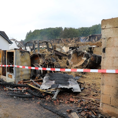 Blick auf einen abgebrannten Bauernhof, von dem allein noch das Wohngebäude steht.