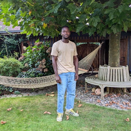 Ein junger Mann steht in einem Garten.