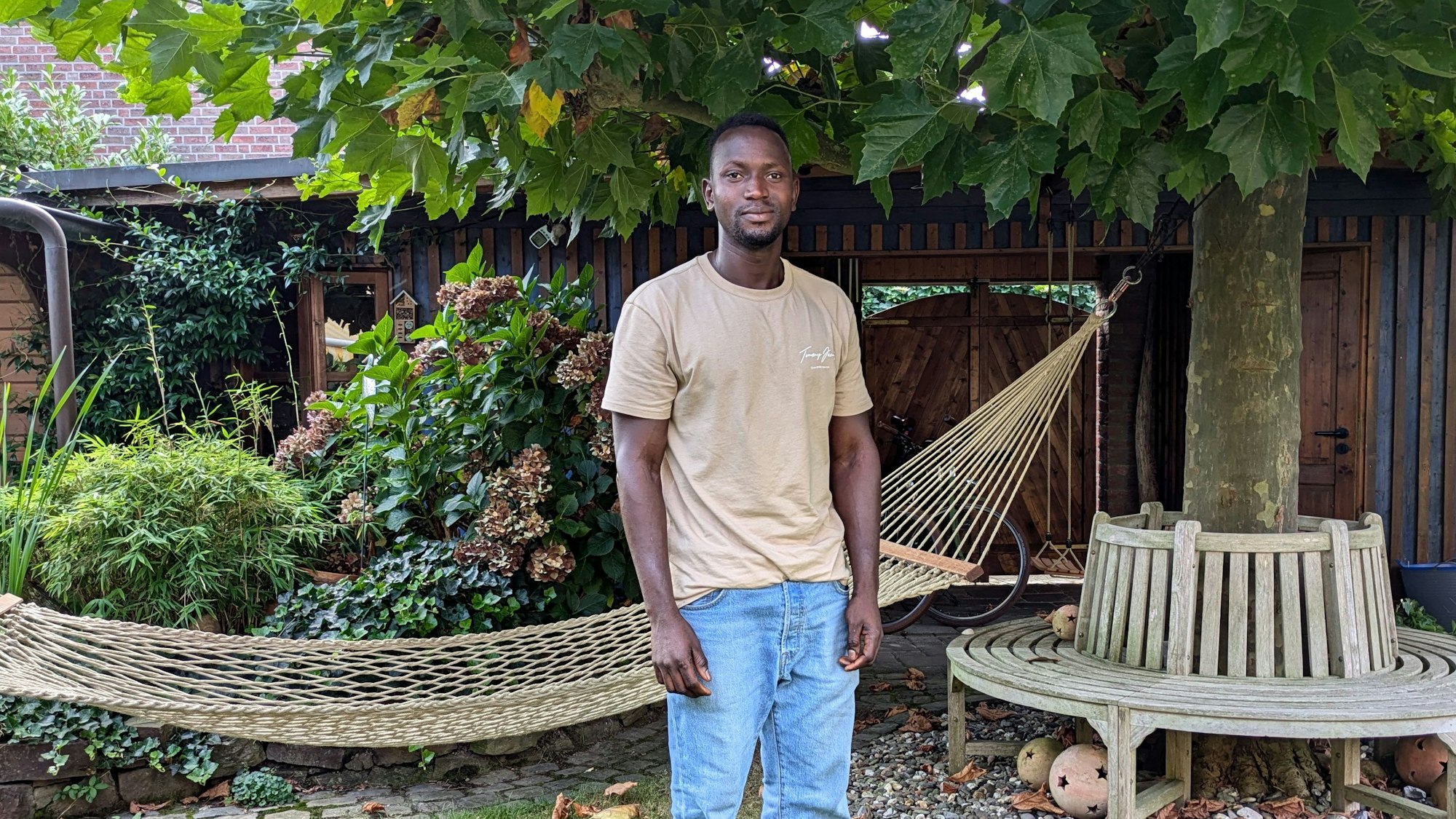 Ein junger Mann steht in einem Garten.