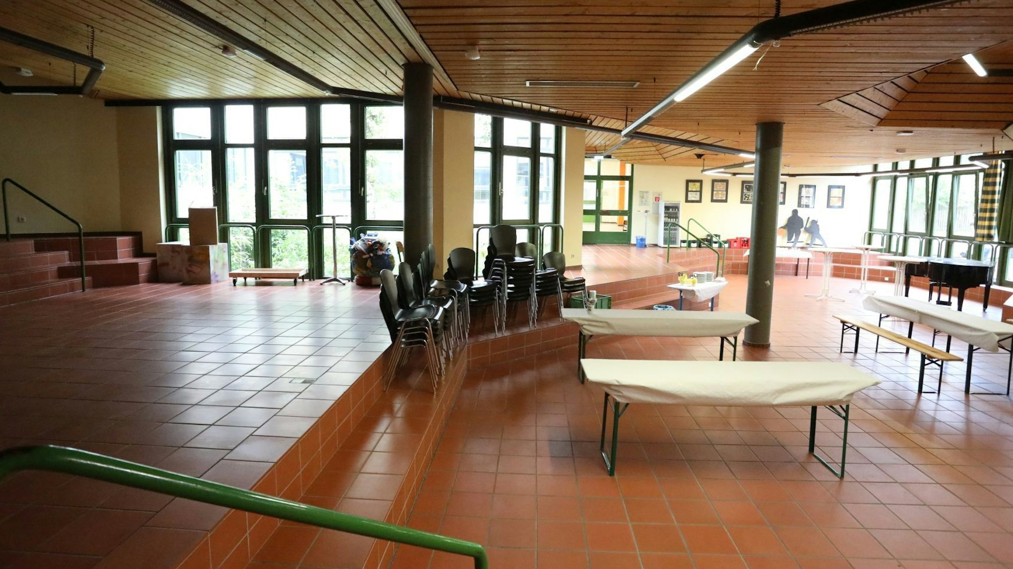 Ein großer Raum mit Tischen und aufeinander gestapelten Stühlen.