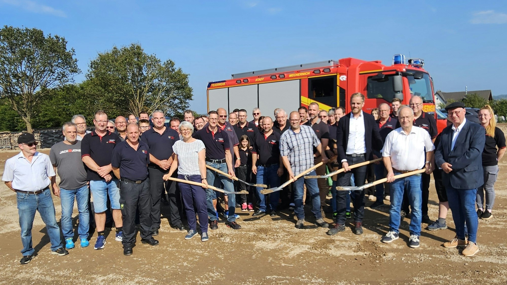 Vertreter von Stadt, Feuerwehr, der Baufirma und des Planungsbüros stehen vor einem Feuerwehrfahrzeug.
