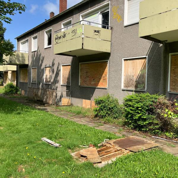 Blick auf einen Wohnblock mit Wohnungen, deren Fenster verrammelt sind.
