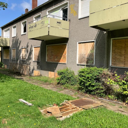 Zu sehen sind leerstehende Wohnhäuser, mit verbretterten Fenstern und Türen.