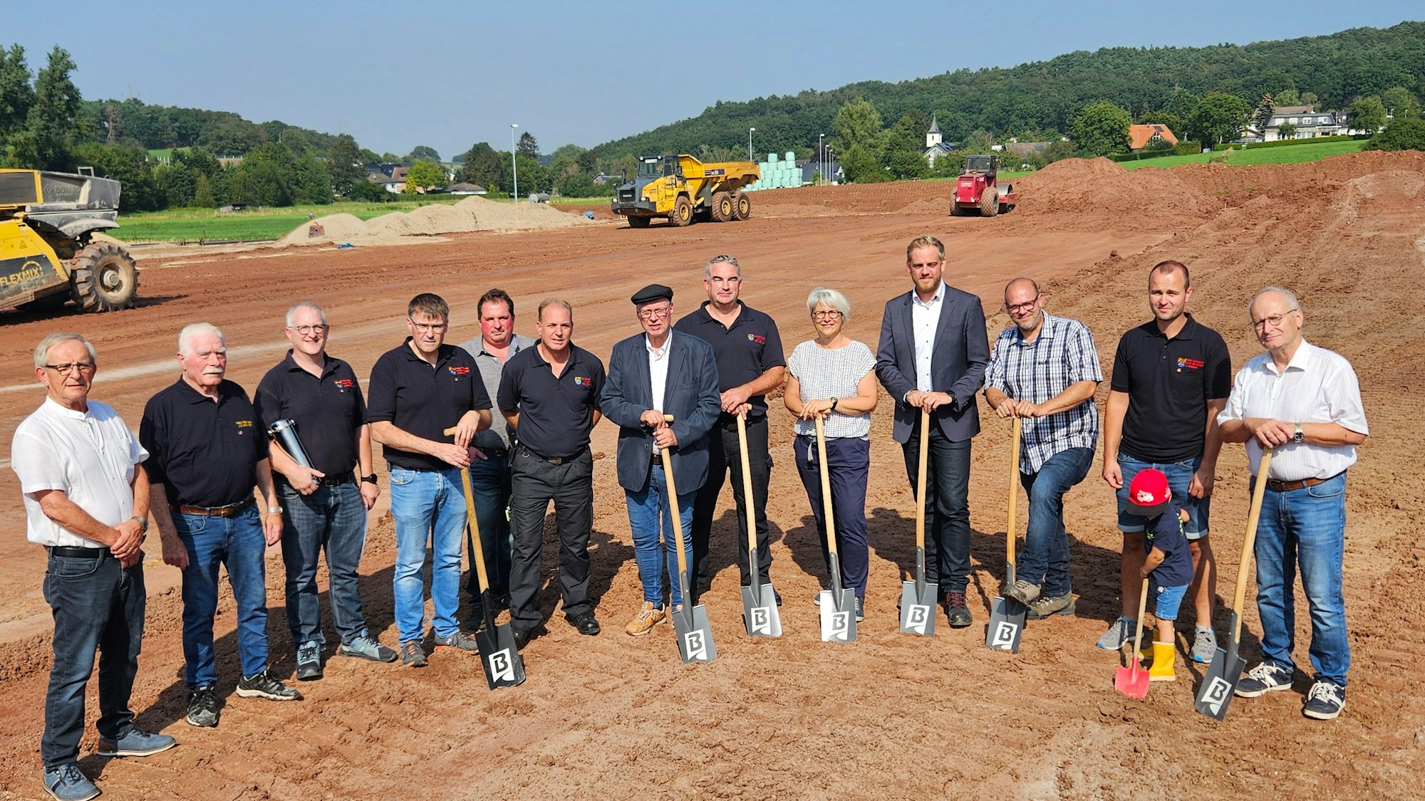 Vertreter von Stadt, Feuerwehr, der Baufirma und des Planungsbüros stehen zum Teil mit Spaten nebeneinander.