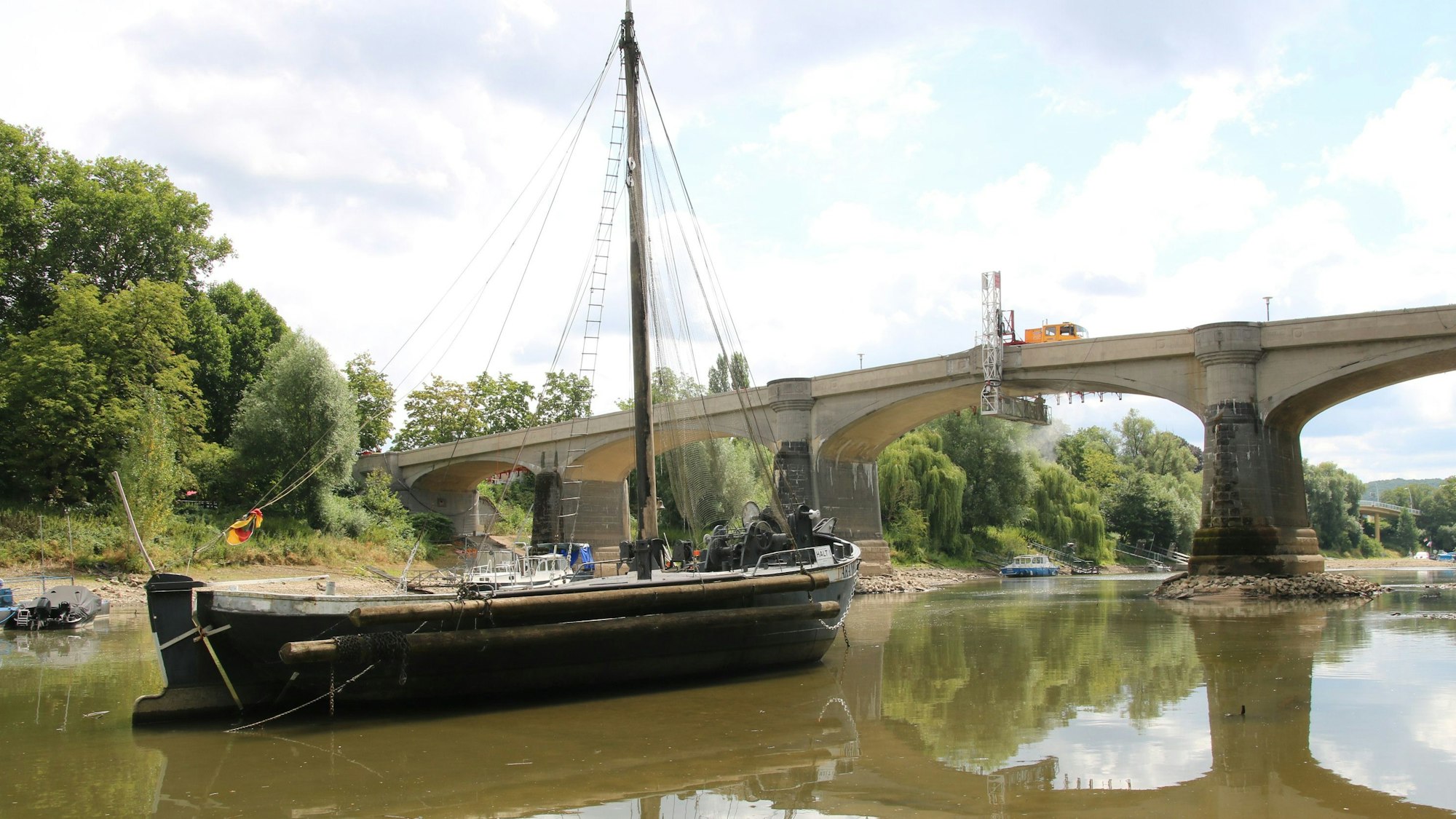 Ein historisches Schiff liegt vor einer Brücke.